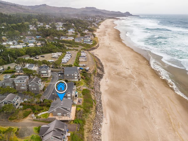 Aerial view showing the property's coastal location, nestled between rolling hills and a pristine sandy beach. The neighborhood offers direct access to miles of peaceful shoreline.